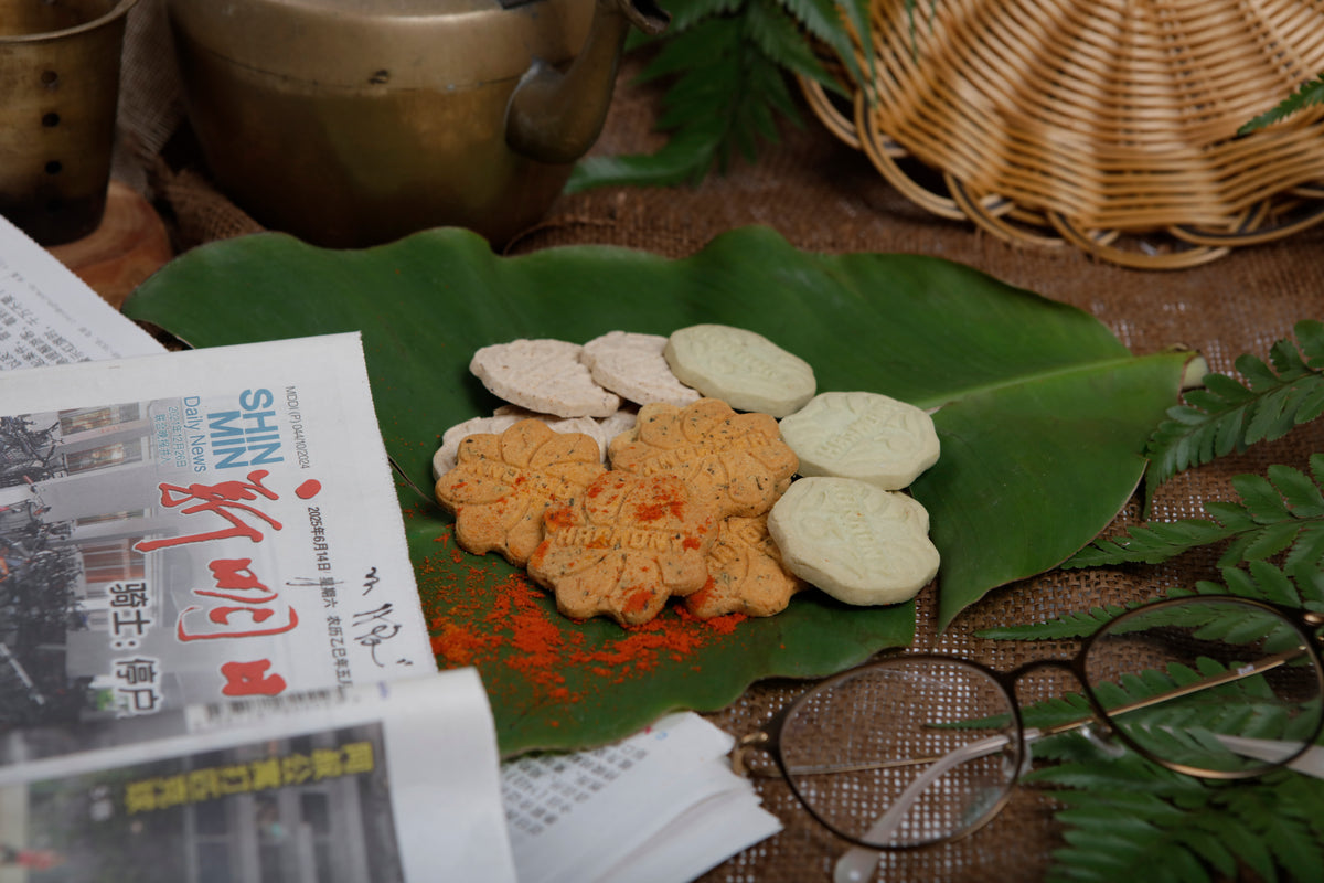 Harmony cookies on a banana leaf beside a newspaper and a pair of glasses
