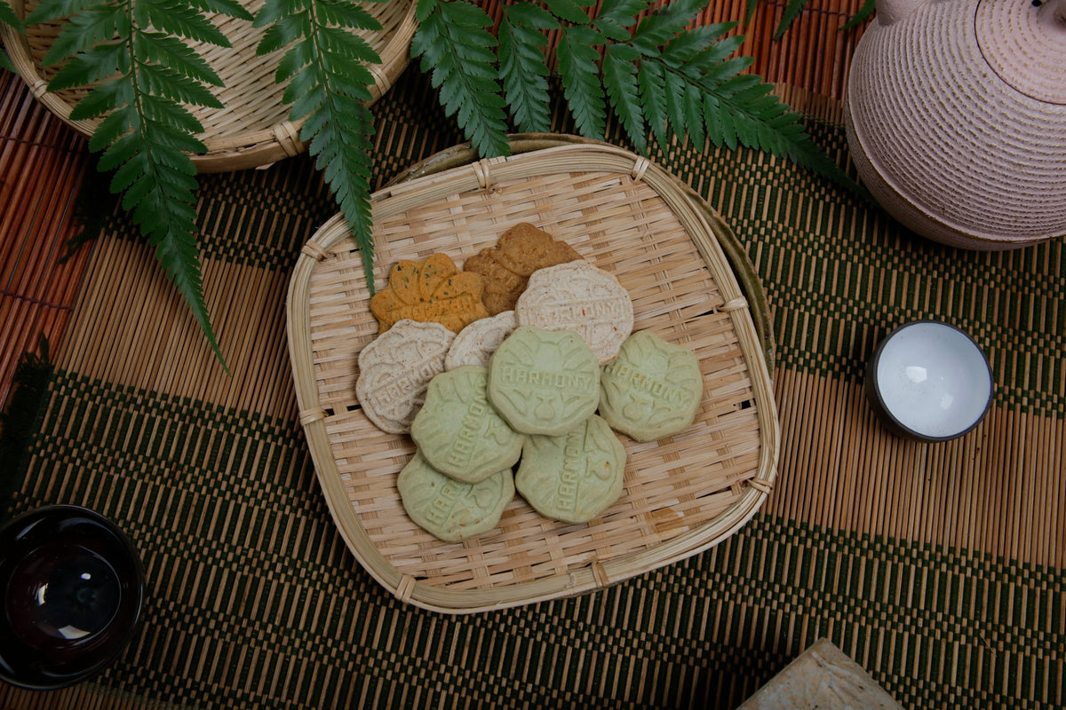 Harmony cookies in a rattan tray beside a teapot and a fern